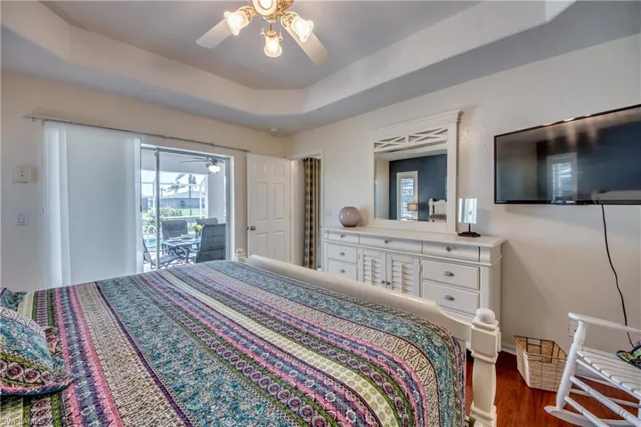 Bedroom featuring a raised ceiling, ceiling fan, dark hardwood / wood-style flooring, and access to exterior