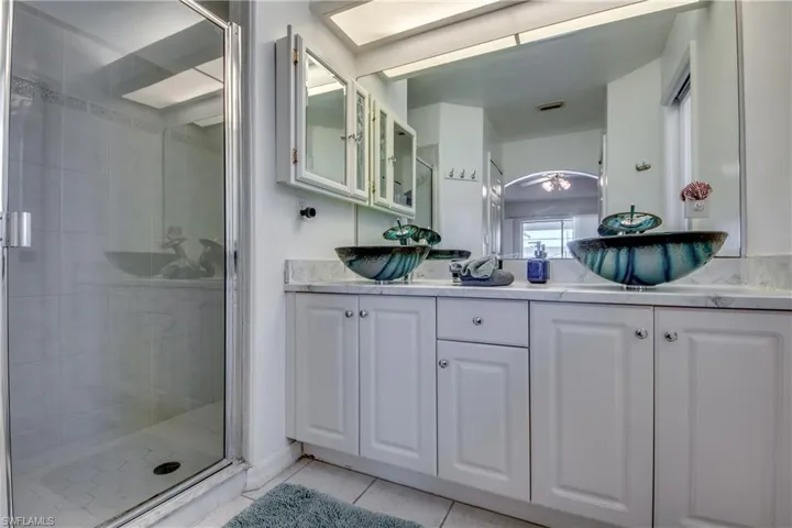 Bathroom featuring tile patterned flooring, vanity, walk in shower, and ceiling fan