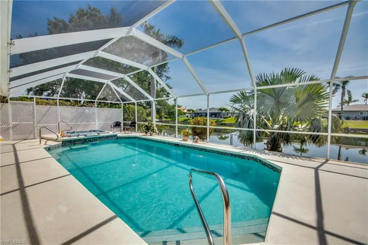 View of pool with glass enclosure, a water view, and a patio