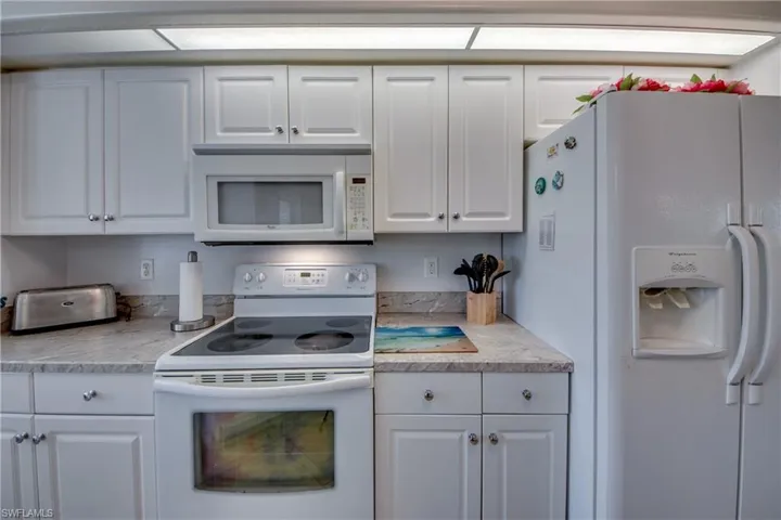 Kitchen featuring white cabinets and white appliances