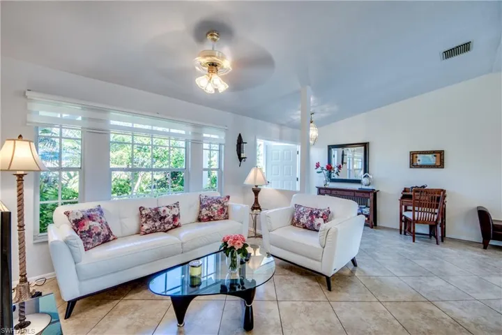 Tiled living room with ceiling fan and vaulted ceiling