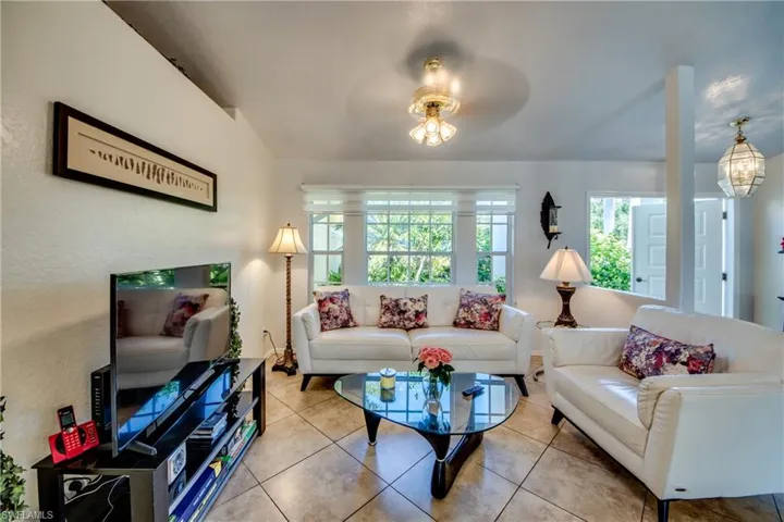 Living room with tile patterned flooring and ceiling fan with notable chandelier