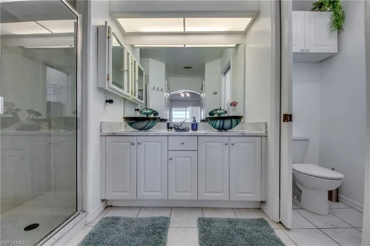 Bathroom featuring tile patterned flooring, vanity, an enclosed shower, and toilet