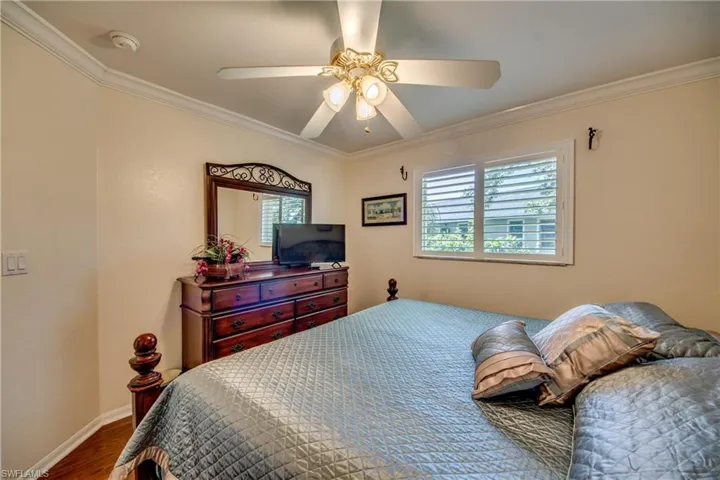 Bedroom with hardwood / wood-style flooring, ceiling fan, and ornamental molding
