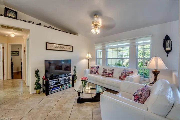 Living room featuring ceiling fan, light tile patterned floors, and lofted ceiling