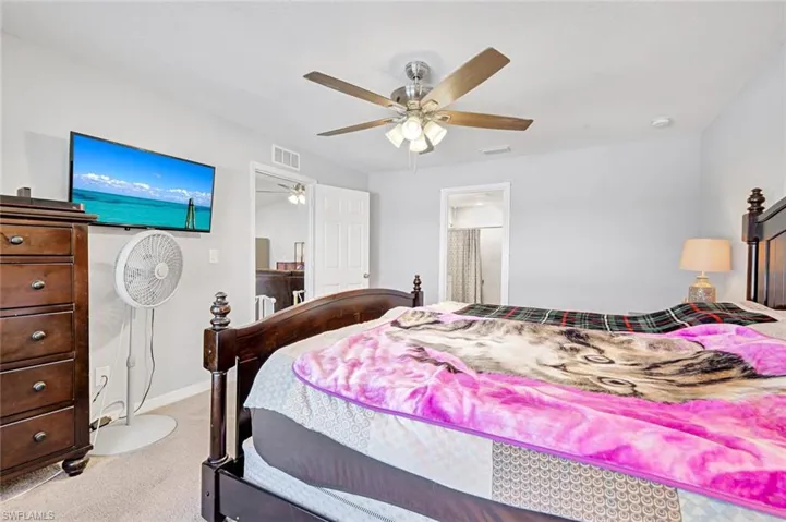 Bedroom featuring a ceiling fan, light carpet, and ensuite bathroom