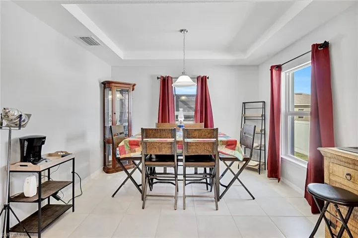 Dining area with a tray ceiling and light tile patterned floors