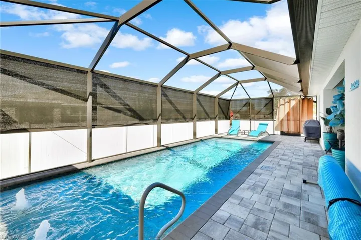 Swimming pool featuring a sunroom, glass enclosure, and a patio area