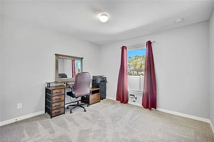 Carpeted office space with baseboards and a textured ceiling
