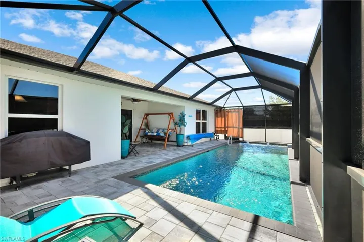 Outdoor pool featuring a sunroom, glass enclosure, and a patio