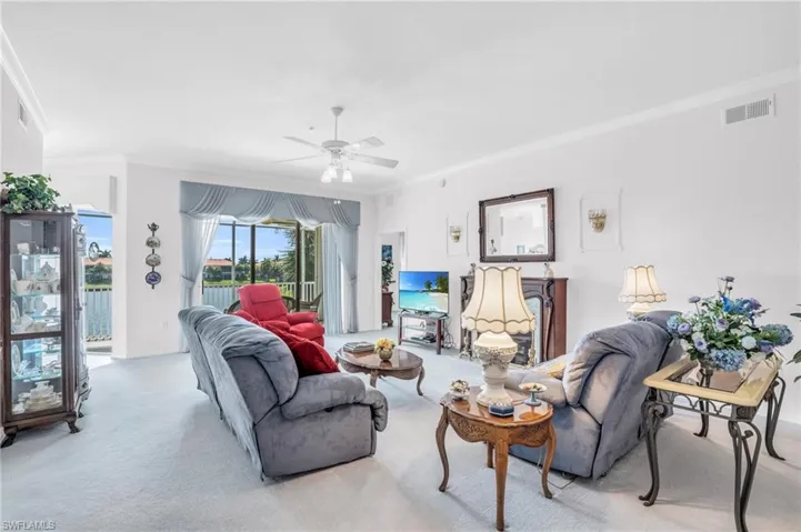 Carpeted living room with ceiling fan and ornamental molding