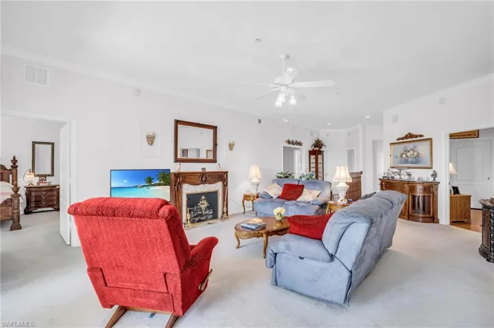 Carpeted living room with a high end fireplace, crown molding, and ceiling fan