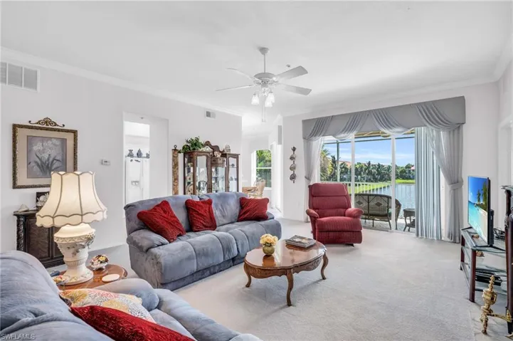 Living room with ceiling fan, carpet, and ornamental molding