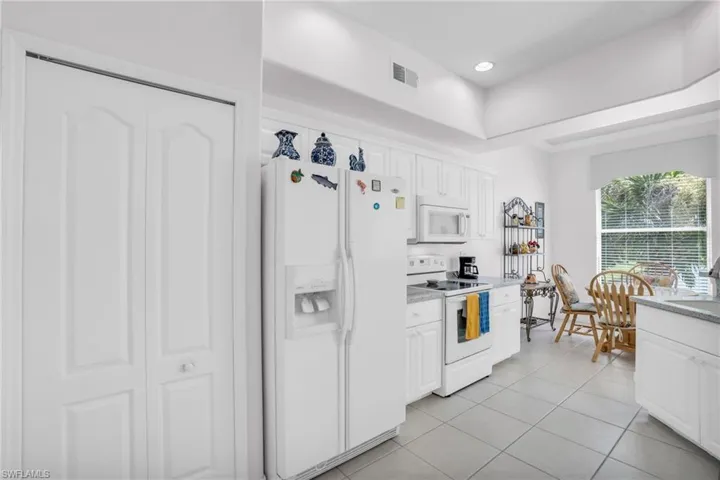 Kitchen with sink, white cabinetry, light tile patterned floors, and white appliances