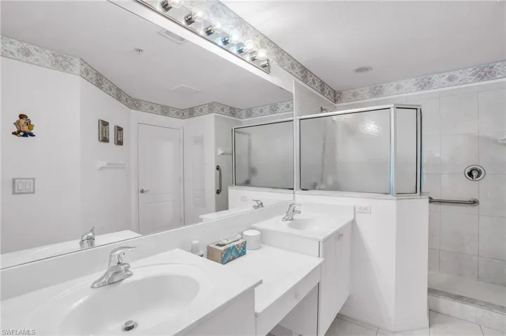 Bathroom featuring double vanity, tile patterned flooring, and a shower with door