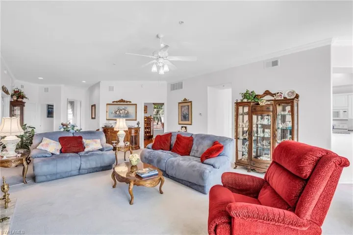 Carpeted living room featuring crown molding and ceiling fan