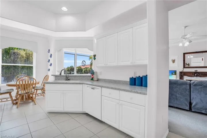 Kitchen with light tile patterned floors, white cabinetry, dishwasher, and ceiling fan