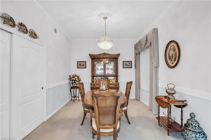 Carpeted dining room featuring crown molding and a chandelier