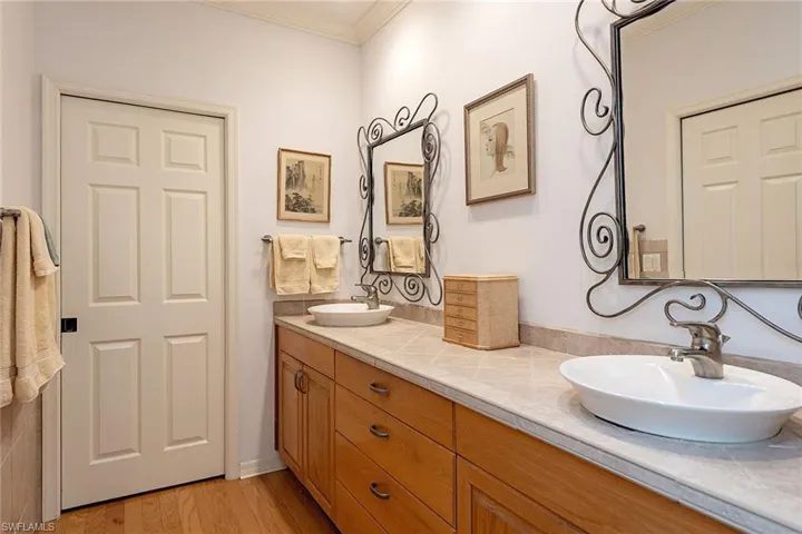 Bathroom featuring crown molding, double vanity, and light wood-style floors
