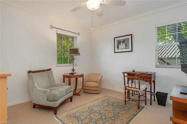 Living area featuring ornamental molding, light carpet, and a ceiling fan