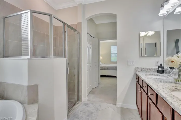 Bathroom featuring ornamental molding, dual vanity, shower with separate bathtub, and tile patterned flooring