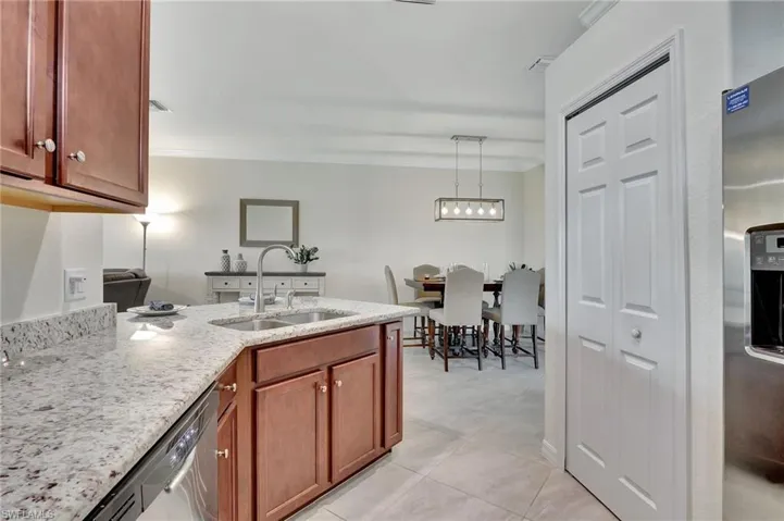 Kitchen with sink, pendant lighting, light stone counters, crown molding, and light tile patterned flooring