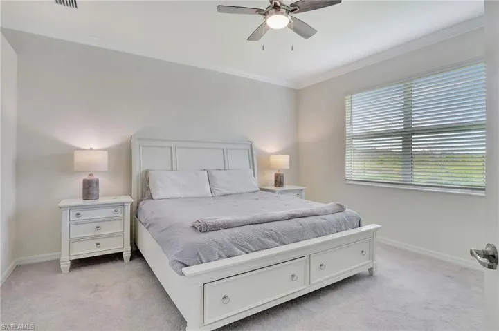 Bedroom featuring light carpet, ornamental molding, and ceiling fan