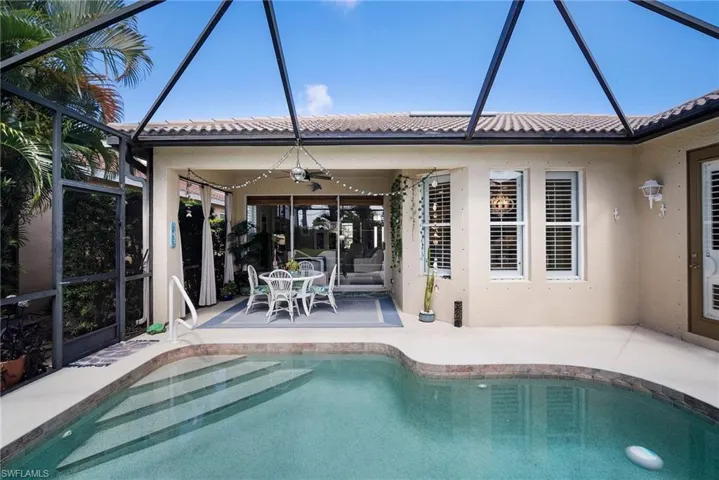 View of pool with a patio, ceiling fan, and glass enclosure