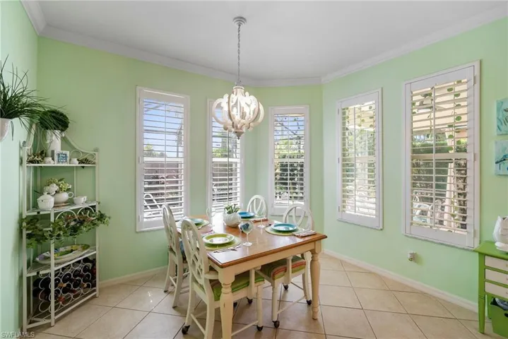Tiled dining area featuring ornamental molding and a notable chandelier