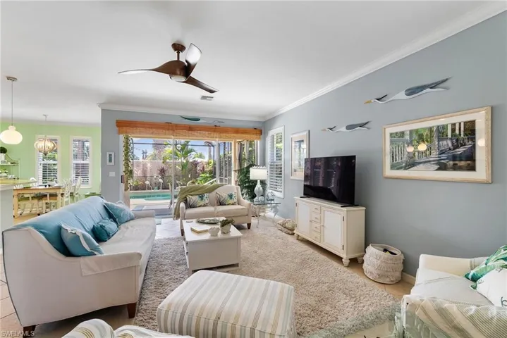 Tiled living room featuring crown molding and ceiling fan