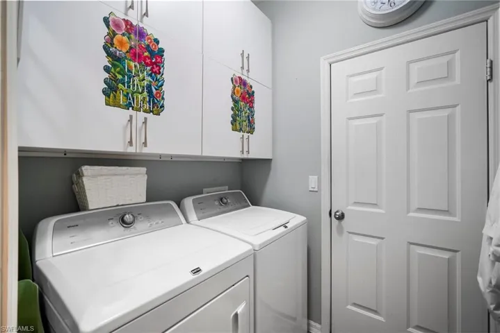 Clothes washing area featuring cabinets and washing machine and clothes dryer
