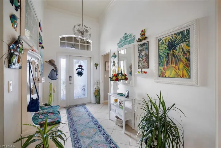 Tiled foyer entrance featuring ornamental molding, a notable chandelier, and a towering ceiling