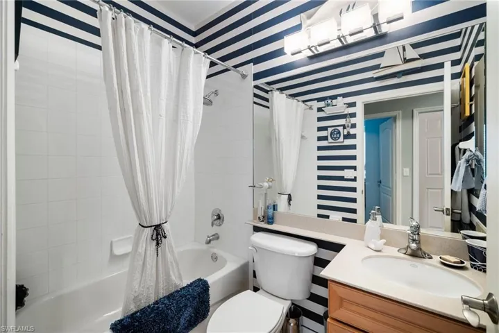 Full bathroom featuring shower / bath combo with shower curtain, toilet, and vanity