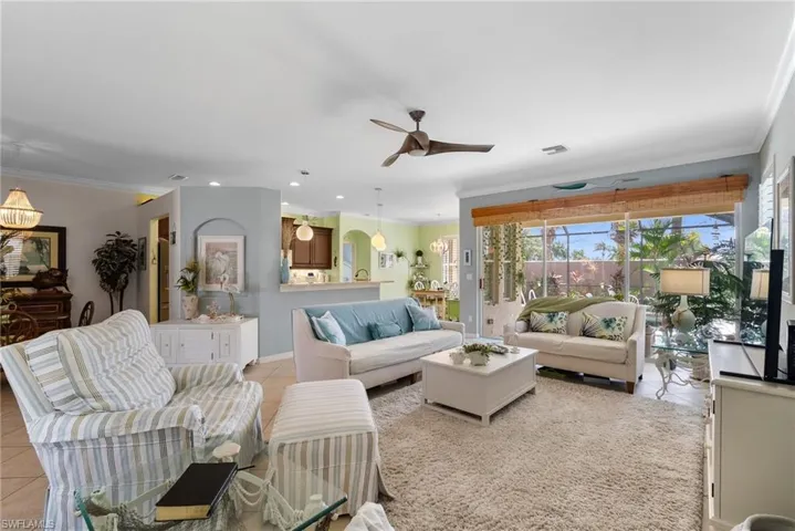 Tiled living room with crown molding and ceiling fan