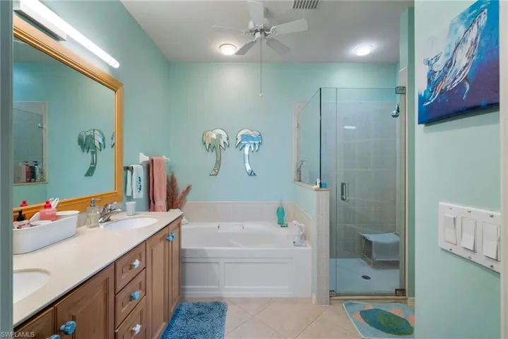 Bathroom featuring separate shower and tub, dual vanity, tile patterned floors, and ceiling fan