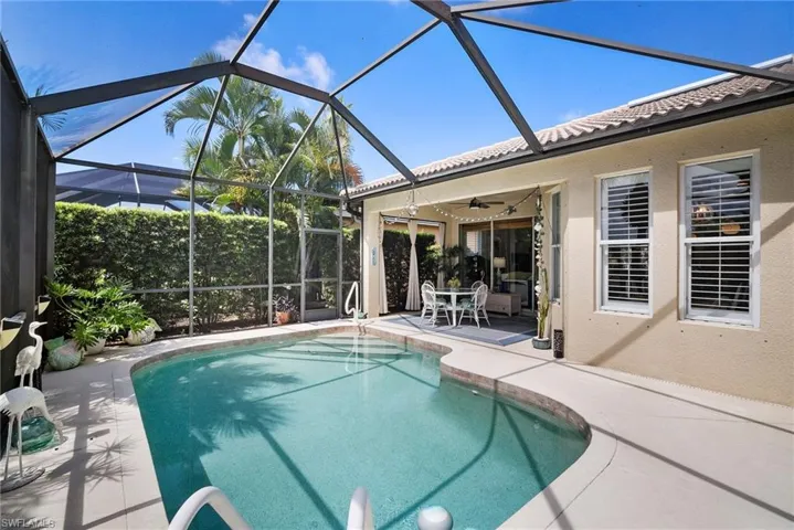 View of pool with a patio area, ceiling fan, and glass enclosure