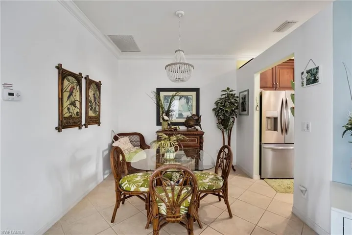 Tiled dining area featuring ornamental molding and an inviting chandelier
