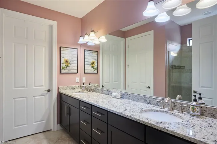 Full bath featuring double vanity, a stall shower, and light tile patterned flooring