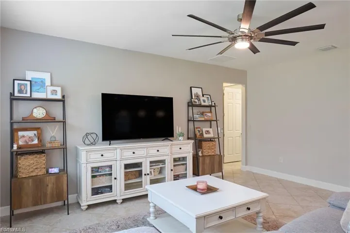 Living area featuring light tile patterned floors and a ceiling fan