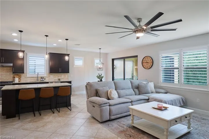 Living room with recessed lighting, light tile patterned floors, a ceiling fan, and a chandelier