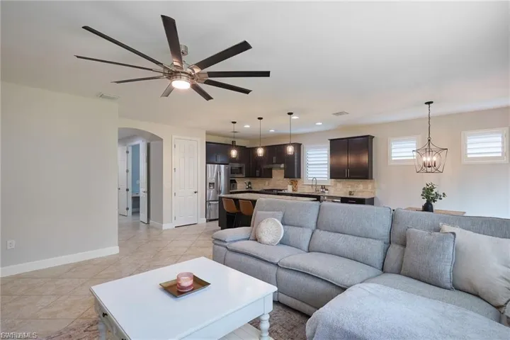 Living room with arched walkways, a chandelier, recessed lighting, light tile patterned floors, and a ceiling fan