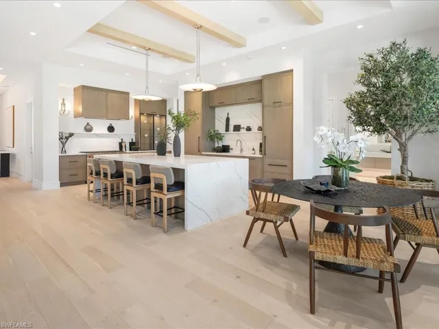Kitchen featuring light countertops, beam ceiling, a spacious island, light wood-type flooring, and a breakfast bar area