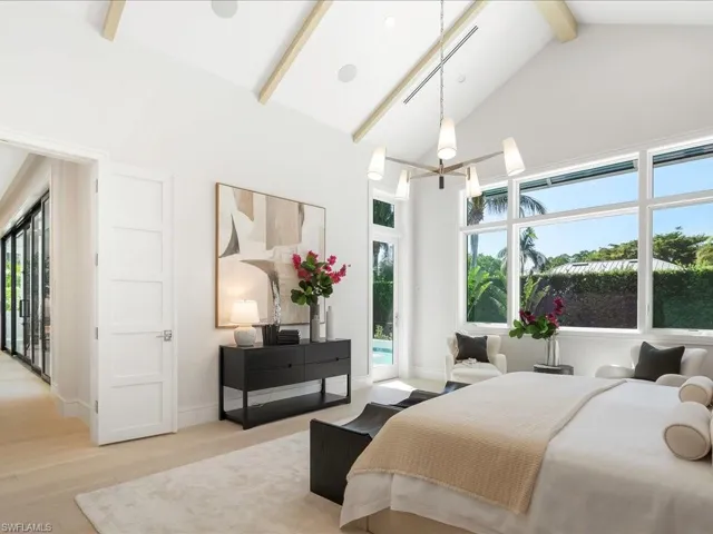 Bedroom featuring high vaulted ceiling, beam ceiling, access to exterior, light wood-style floors, and an inviting chandelier