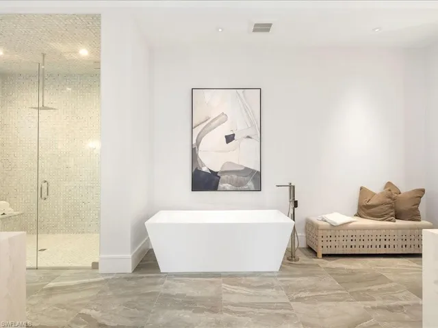 Bathroom with baseboards, a soaking tub, marble finish floor, a stall shower, and visible vents