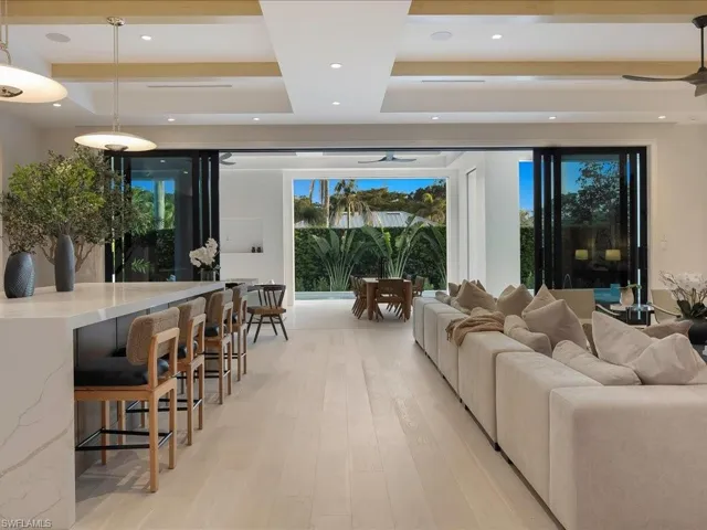 Living area featuring a ceiling fan, a raised ceiling, light wood finished floors, and recessed lighting