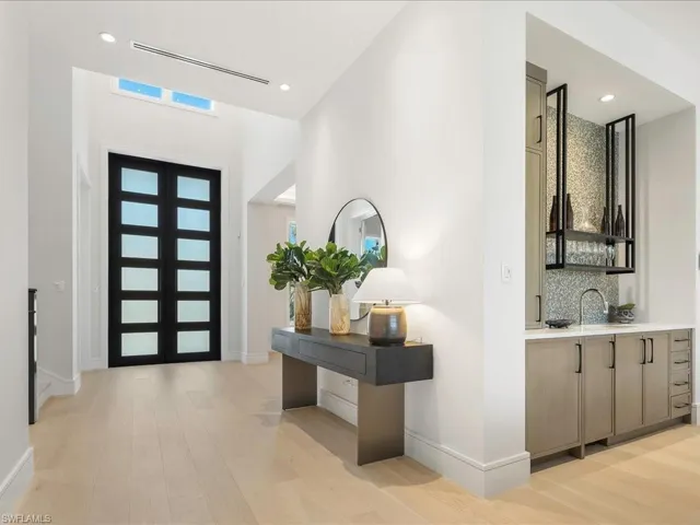 Foyer entrance with visible vents, light wood-style flooring, baseboards, recessed lighting, and wet bar