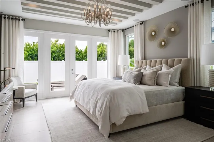 Bedroom featuring access to outside, multiple windows, a chandelier, and beamed ceiling