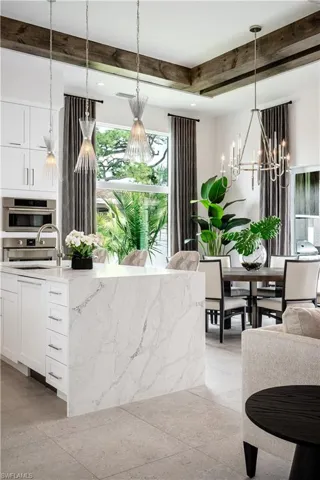 Kitchen with a kitchen breakfast bar, white cabinetry, backsplash, and light stone counters