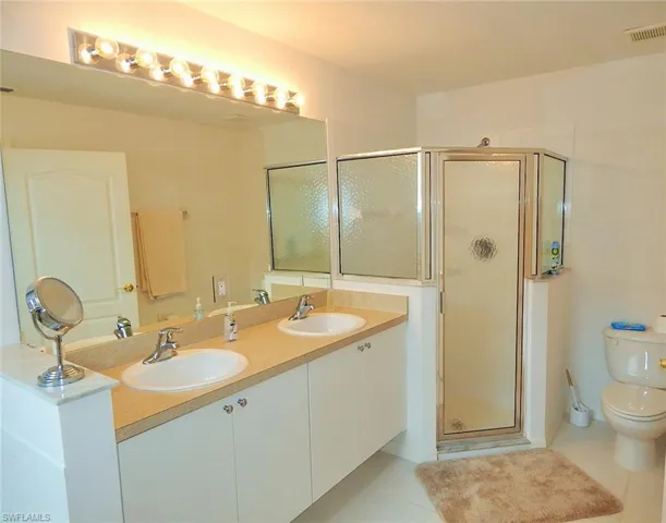 Full bathroom with tile patterned floors, a shower stall, and double vanity