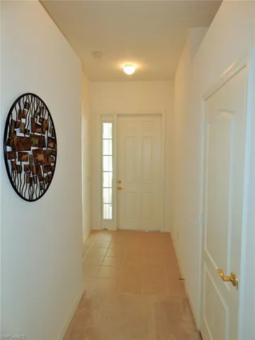 Foyer featuring light tile patterned flooring and light colored carpet